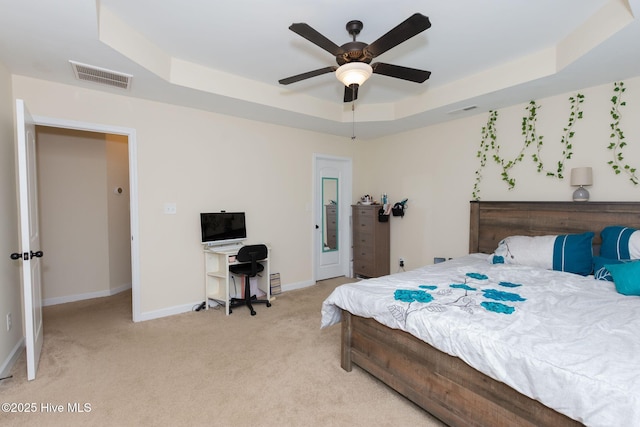 bedroom featuring light carpet, a tray ceiling, visible vents, and baseboards