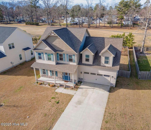 view of front facade featuring concrete driveway, an attached garage, fence, a porch, and a front yard