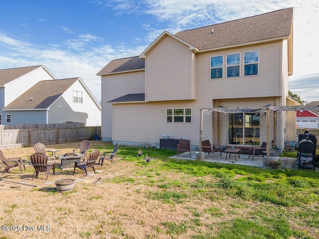 back of property with a fire pit, a patio, a yard, and fence