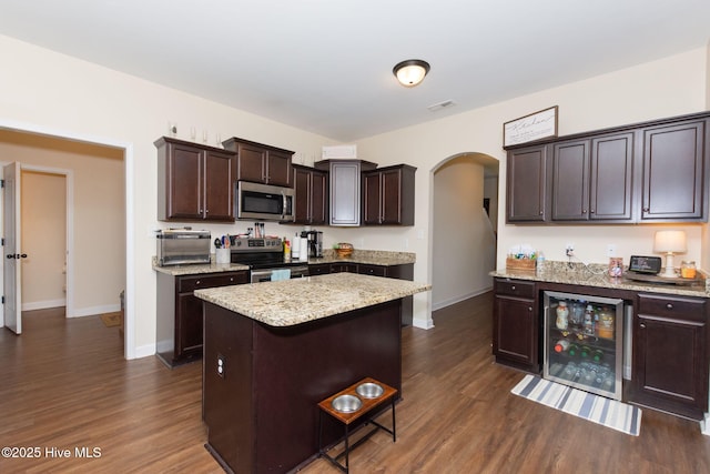 kitchen with arched walkways, wine cooler, dark brown cabinetry, stainless steel appliances, and visible vents