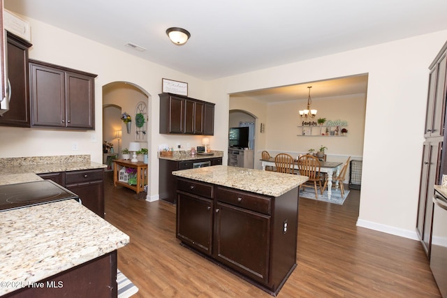 kitchen with arched walkways, dark wood finished floors, a kitchen island, hanging light fixtures, and dark brown cabinets