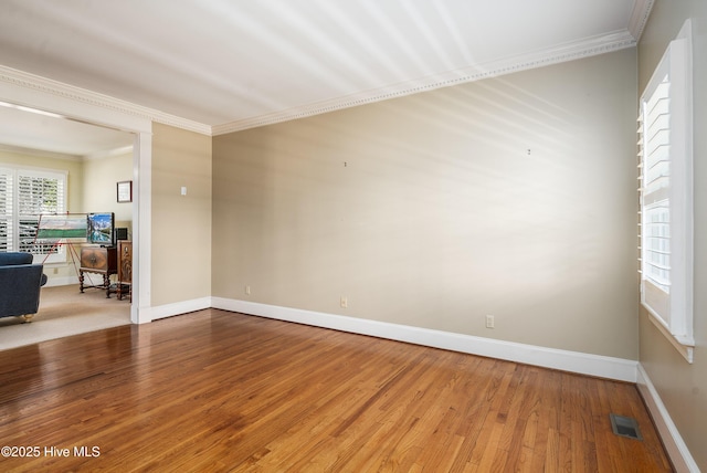 spare room with baseboards, visible vents, crown molding, and hardwood / wood-style floors