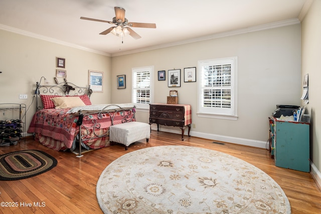 bedroom featuring visible vents, baseboards, a ceiling fan, wood finished floors, and crown molding