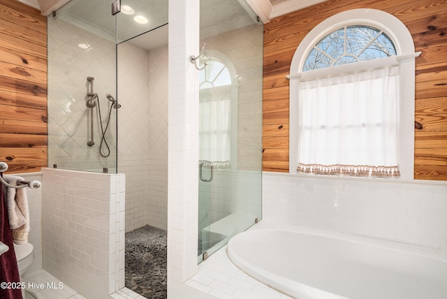 full bath with a garden tub, crown molding, a tile shower, and wooden walls