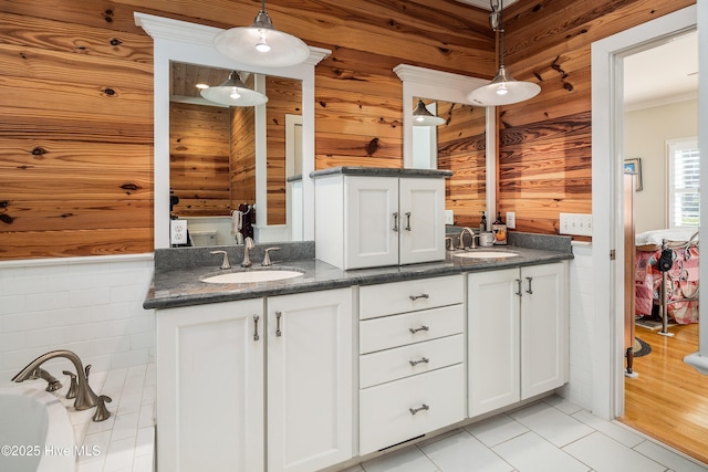 full bathroom featuring double vanity, wood walls, and a sink