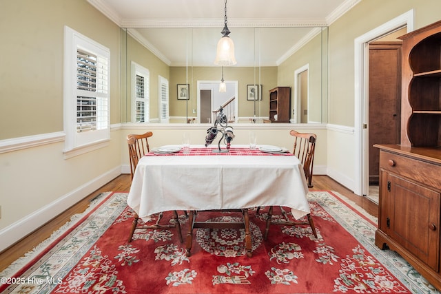 dining space with crown molding, baseboards, and wood finished floors