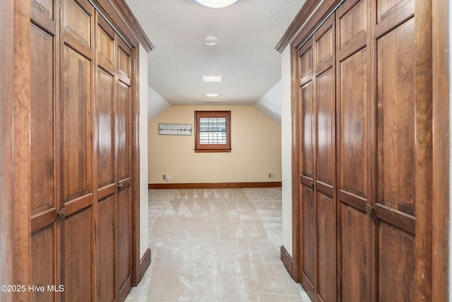 hallway with lofted ceiling, a textured ceiling, and baseboards