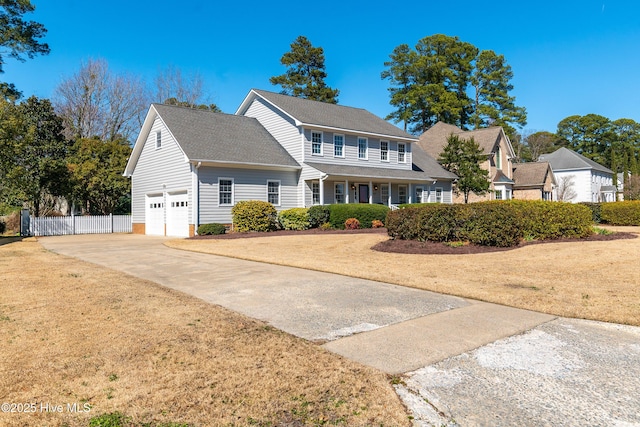 colonial-style house featuring a shingled roof, concrete driveway, an attached garage, a front yard, and fence