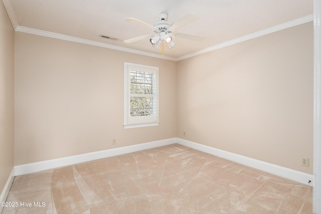 spare room featuring light carpet, visible vents, baseboards, a ceiling fan, and crown molding