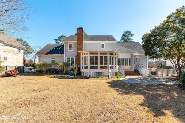 back of house with a yard, a chimney, fence, and a sunroom