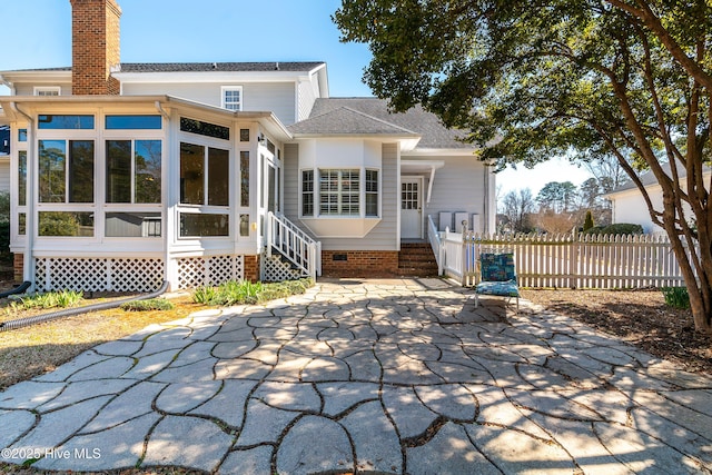 back of house featuring fence, a sunroom, roof with shingles, crawl space, and a chimney