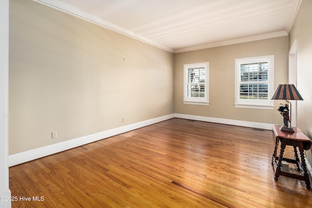 spare room featuring baseboards, ornamental molding, and wood finished floors