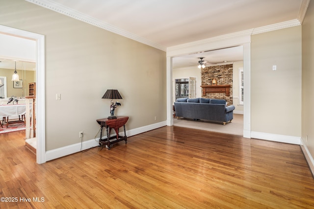 unfurnished room with ornamental molding, a fireplace, ceiling fan, and light wood-style flooring