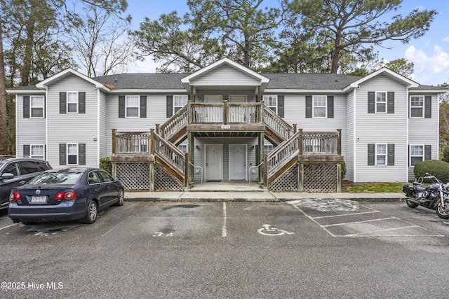 townhome / multi-family property featuring uncovered parking, stairs, and a shingled roof