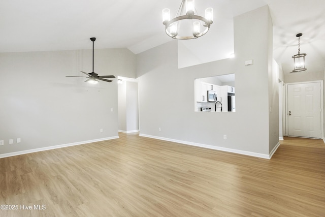 unfurnished living room featuring light wood-type flooring, baseboards, high vaulted ceiling, and ceiling fan with notable chandelier