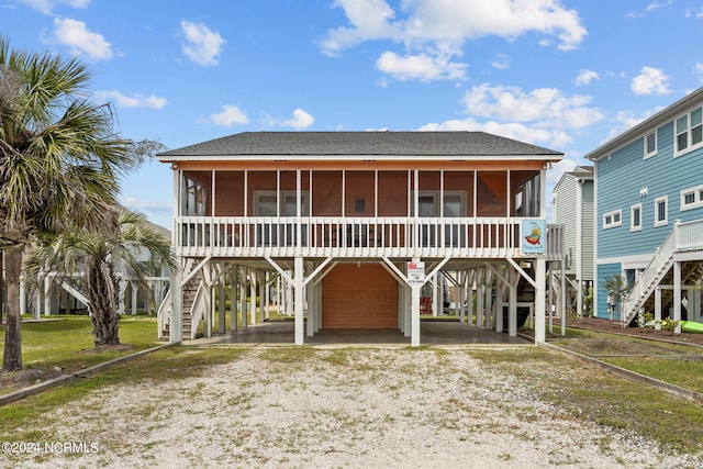 view of front of house with stairs, a carport, and a sunroom