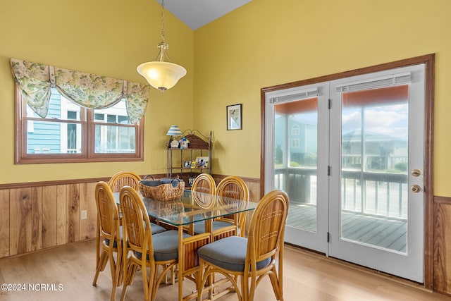 dining area featuring lofted ceiling, a wainscoted wall, light wood-style flooring, and wood walls