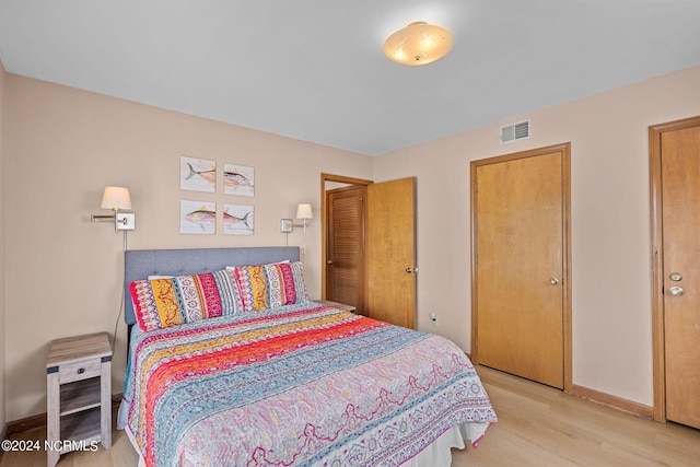 bedroom featuring baseboards, visible vents, and wood finished floors