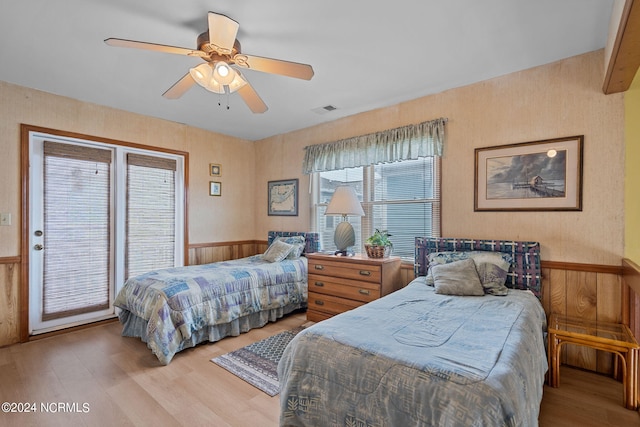 bedroom featuring wood finished floors, a ceiling fan, visible vents, access to exterior, and wainscoting