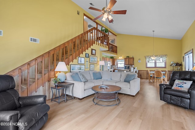 living area with high vaulted ceiling, stairway, visible vents, and light wood-style floors