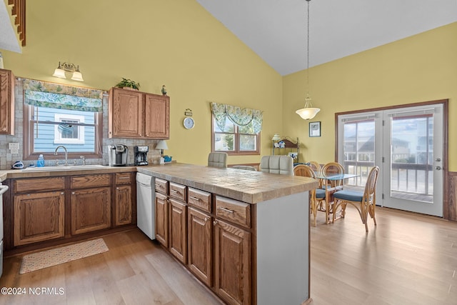 kitchen featuring brown cabinetry, dishwasher, a peninsula, and a sink