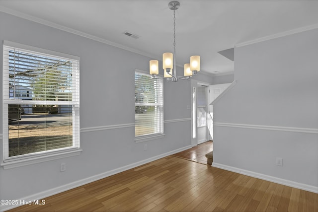 unfurnished dining area with crown molding, wood finished floors, visible vents, baseboards, and an inviting chandelier