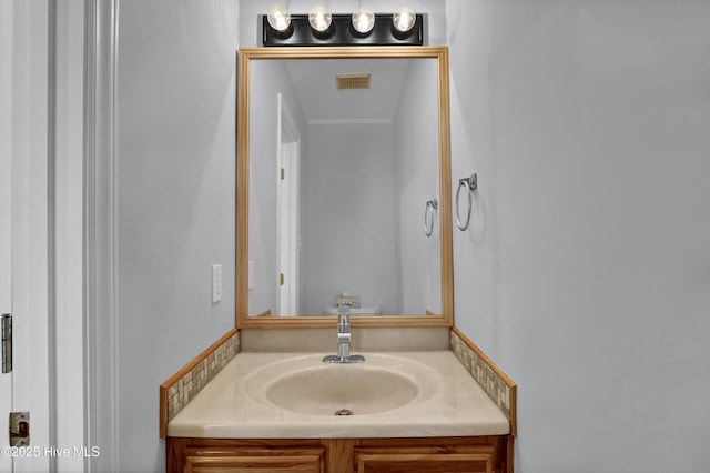 bathroom with visible vents, crown molding, and vanity