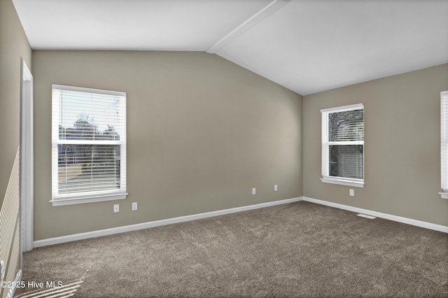 carpeted spare room featuring baseboards, vaulted ceiling, and a wealth of natural light