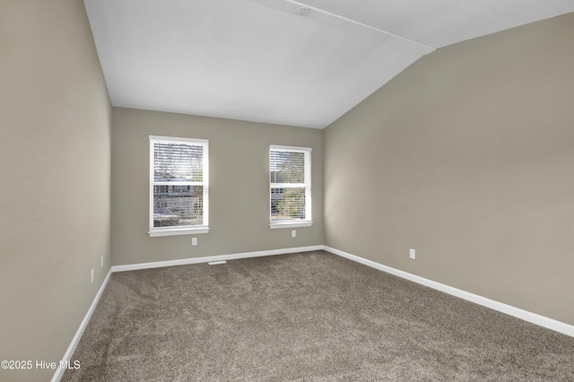 unfurnished room featuring lofted ceiling, dark colored carpet, and baseboards