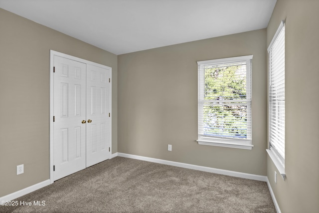 unfurnished bedroom featuring carpet, baseboards, and a closet