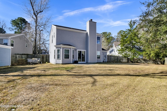 rear view of house with a chimney, fence, and a lawn