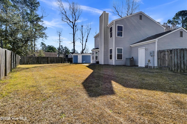 view of yard with an outbuilding, a storage shed, central AC unit, and a fenced backyard