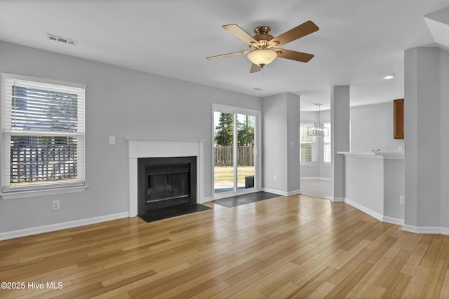 unfurnished living room featuring baseboards, a fireplace with flush hearth, visible vents, and light wood-style floors