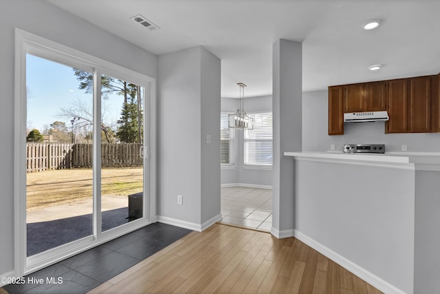 kitchen with visible vents, range, wood finished floors, light countertops, and under cabinet range hood