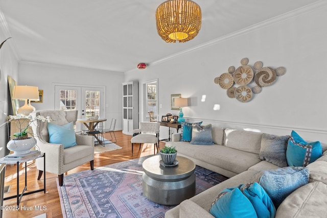 living area with crown molding, wood finished floors, and french doors