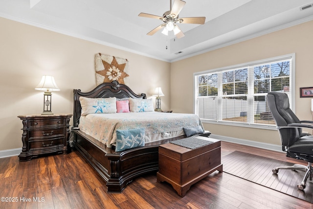 bedroom featuring a raised ceiling, wood finished floors, baseboards, and visible vents