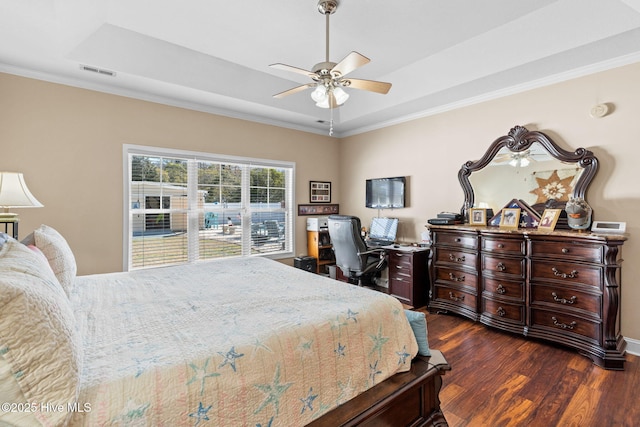 bedroom with visible vents, a tray ceiling, dark wood-style floors, crown molding, and ceiling fan