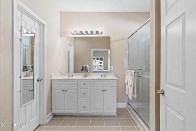 bathroom featuring a sink, double vanity, a shower stall, and tile patterned flooring