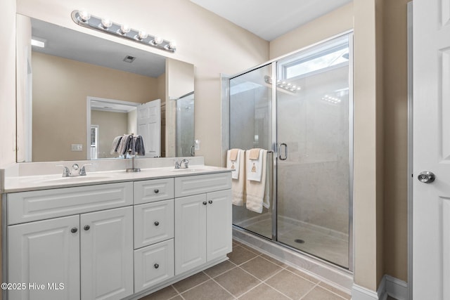 full bath featuring a sink, double vanity, a shower stall, and tile patterned flooring