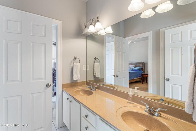 ensuite bathroom featuring toilet, an inviting chandelier, double vanity, and a sink