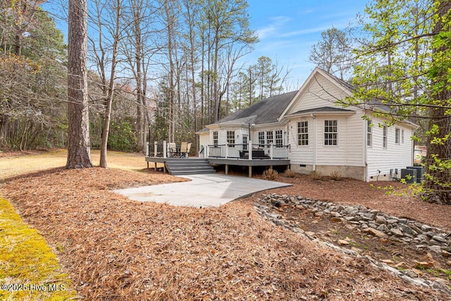 rear view of house with crawl space, central air condition unit, a wooden deck, and a patio