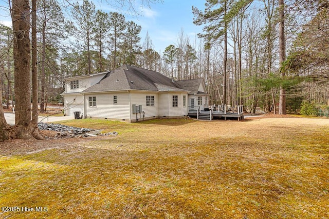 rear view of property with crawl space, a wooden deck, a shingled roof, and a yard