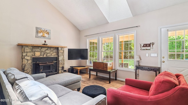 living area with baseboards, high vaulted ceiling, a stone fireplace, and wood finished floors