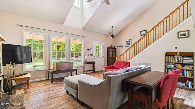 living area featuring visible vents, light wood-style floors, ceiling fan, and high vaulted ceiling