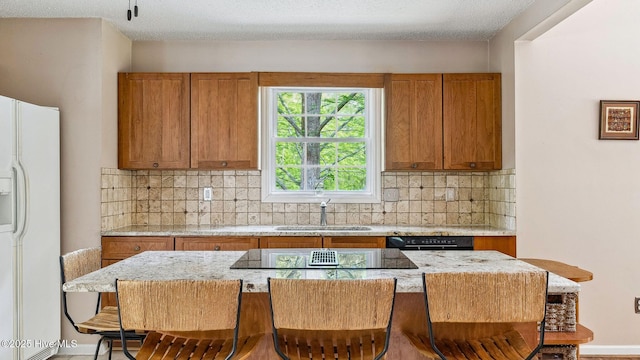 kitchen featuring brown cabinets, a sink, black appliances, and a breakfast bar area