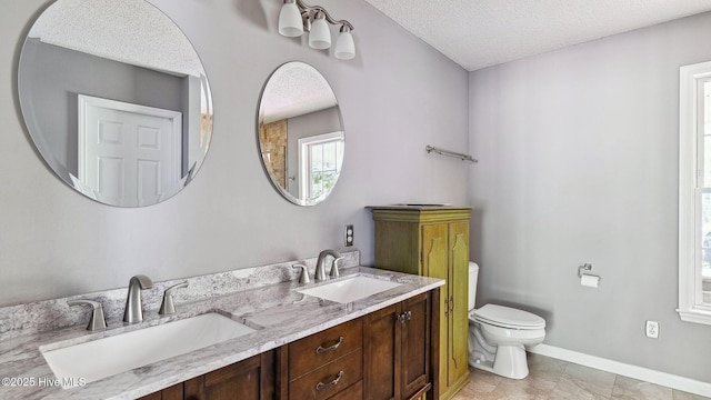 bathroom with baseboards, toilet, a textured ceiling, and a sink