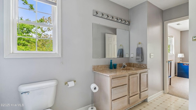 half bath featuring visible vents, baseboards, tile patterned floors, vanity, and toilet