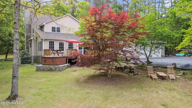 view of yard with a hot tub, a deck, fence, and a garage