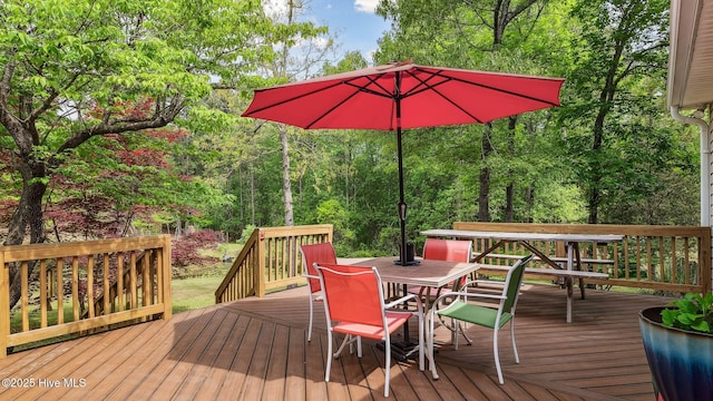 wooden terrace featuring a wooded view and outdoor dining area