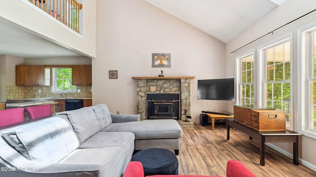 living room featuring light wood-type flooring, a fireplace, and high vaulted ceiling